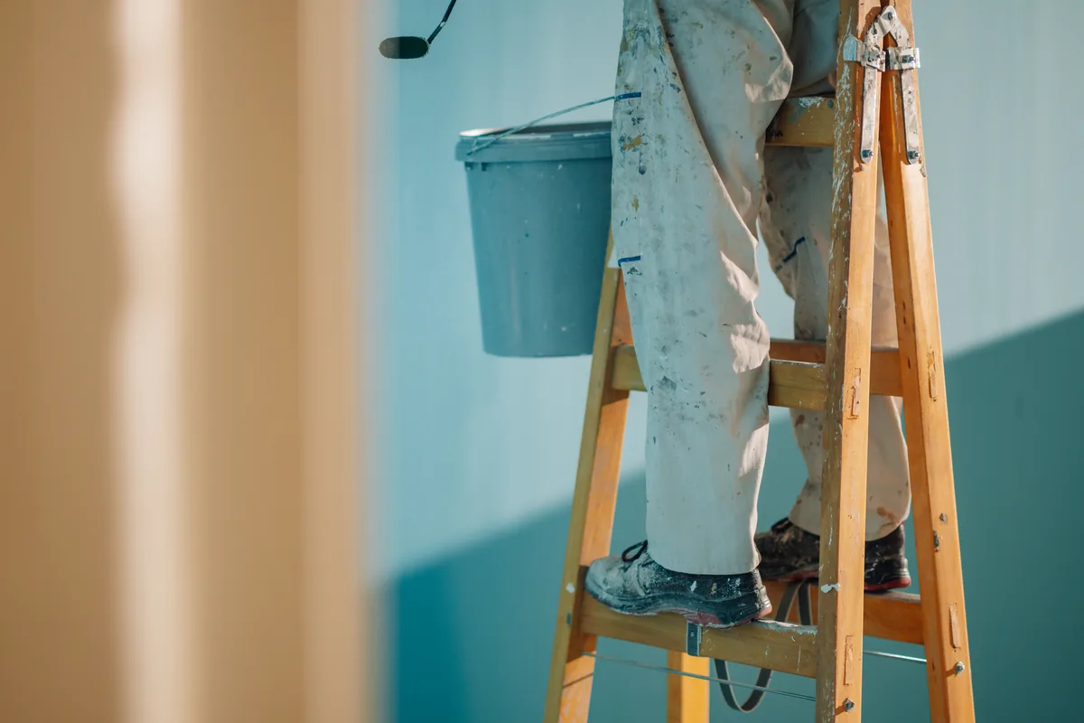 Painter on a ladder rolling an exterior wall