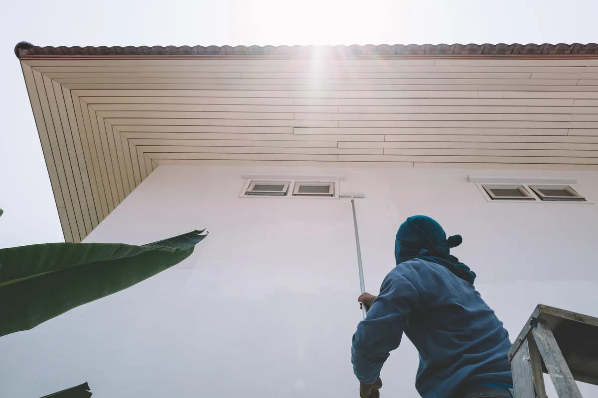 Painter rolling a stucco eave under a tile roof
